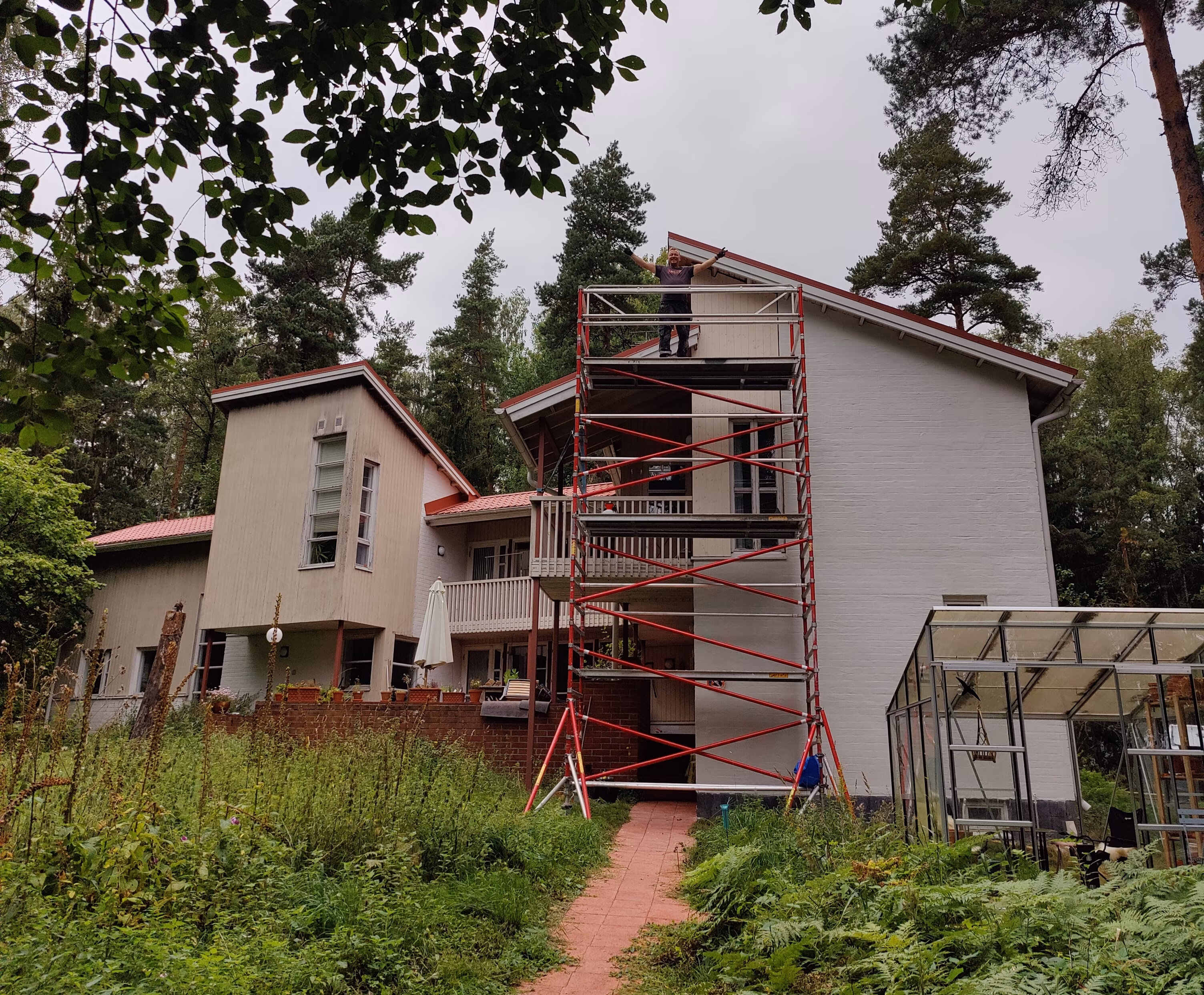 Kuvassa suuri monimuotoinen suuri omakotitalo, jonka korkeassa valkoisessa tiilipintaisessa päädyssä on pystytettynä rakennusteline. Tiiliseinä hohtaa puhtaan valkoisena seinän uudelleen slammauksen jälkeen. Korjausrakentaminen Helsingissä, Espoossa, Vantaalla ja pääkaupunkiseudun lähi kunnissa | Jerodel Oy.
